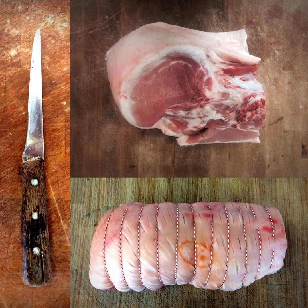 Knife, pork cut and rolled joint on a wooden block