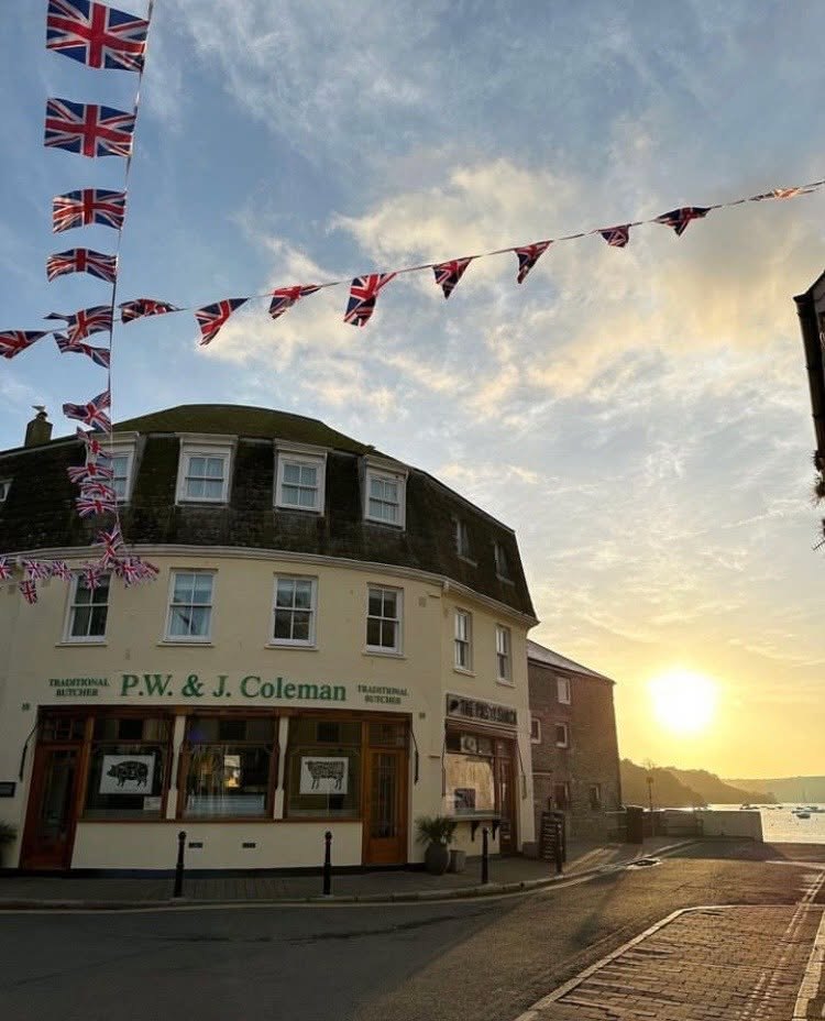 Colemans shopfront on Fore Street with bunting and evening sun